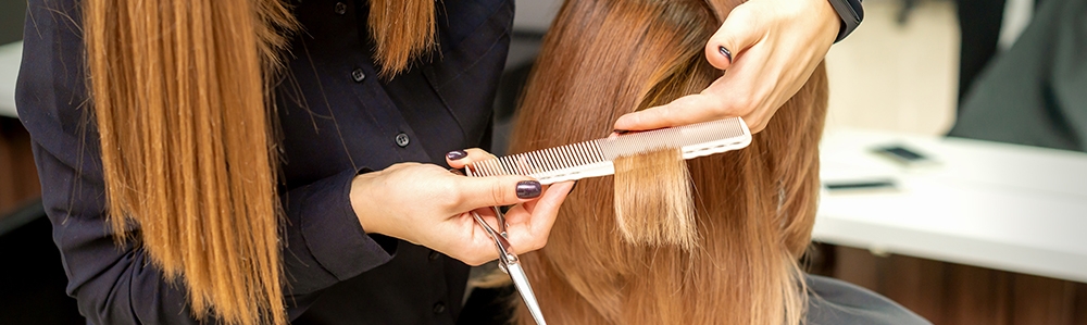 Hairdresser cuts hair to young woman